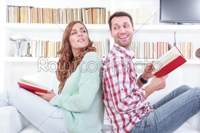 Cheerful couple reading a different books together