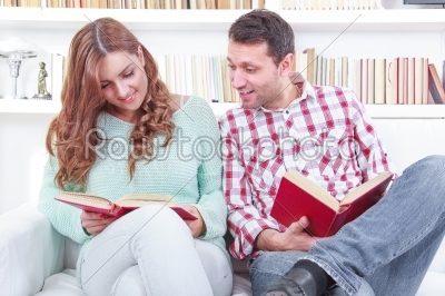 Cheerful young man and woman reading different books together