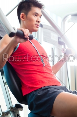 Chinese Man training strength in fitness gym
