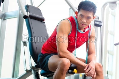 Chinese Man training strength in fitness gym