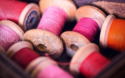 Collection of red spools threads  arranged in a grunge wooden box