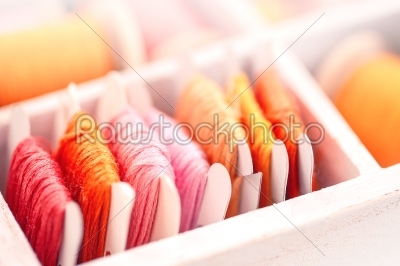 Collection of yellow, red, pink  threads  arranged in a white wooden box