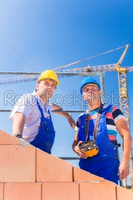 Construction site workers building house with crane