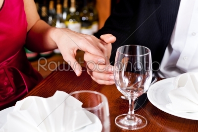 Couple holding hands on a restaurants table