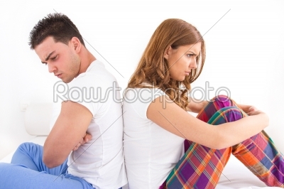 couple ignoring each other sitting back to back on bed during a 