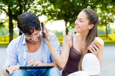couple in city park with tablet computer