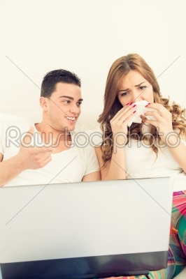 couple in love watching sad movie in bed on laptop