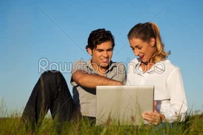 Couple on meadow using wi-fi for Internet 
