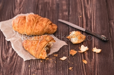 croissant and knife for breakfast on a dark wooden table