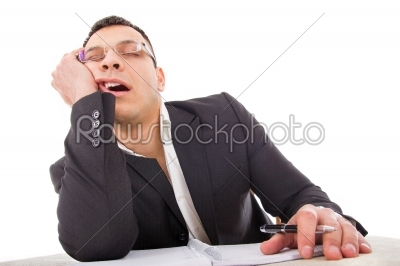 exhausted businessman sleeping at his desk yawning