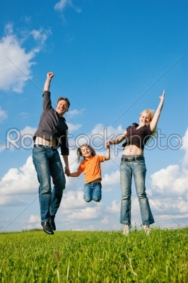 Family jumping on meadow in summer