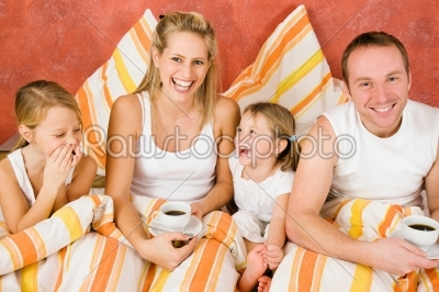 Family of four in bed having breakfast