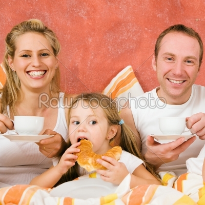 Family of three in bed having breakfast