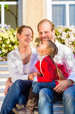 Family on garden bench in front of home