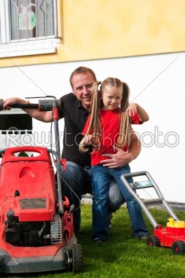 Father and daughter mowing lawn together