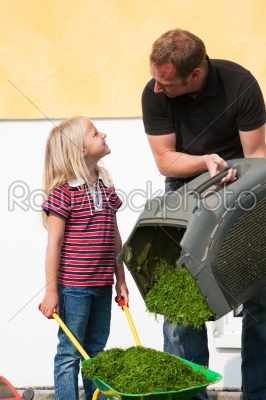 Father and daughter mowing lawn together