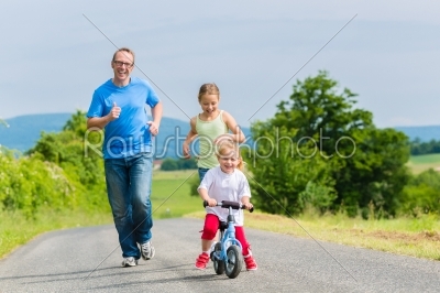 Father and daughters running on street