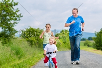 Father and daughters running on street