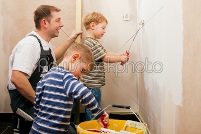 Father painting wall with children