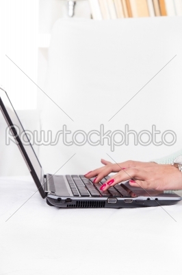 female hands typing on laptop keyboard with red manicure