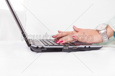 female hands typing on laptop keyboard with red nail polish