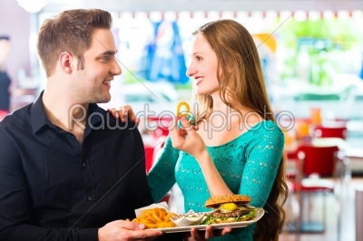 Friends or couple eating fast food with burger and fries 