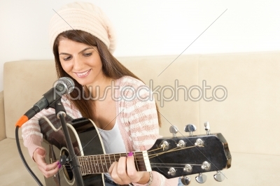 girl playing guitar and singing on microphone