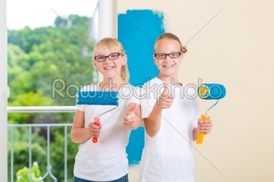 Girls painting a wall in the family home