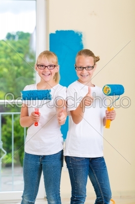 Girls painting a wall in the family home