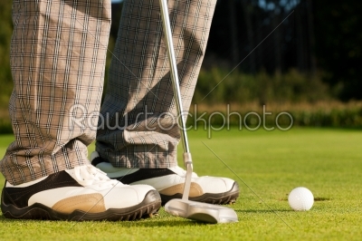Golf player putting ball into hole