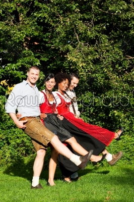 Group of four friends in Bavarian Tracht dancing