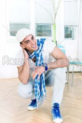 handsome fashion man with a scarf and white cap posing