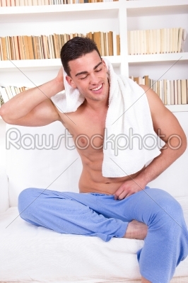 handsome guy on sofa wearing pajamas and towel around neck
