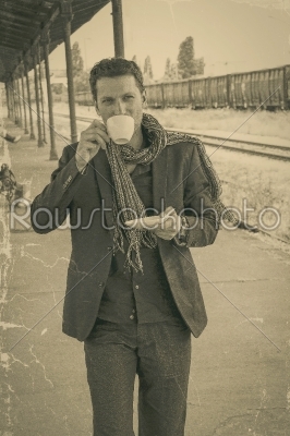 handsome male model drinking coffee at train station