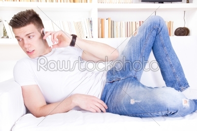 handsome man lying on couch talking on mobile phone
