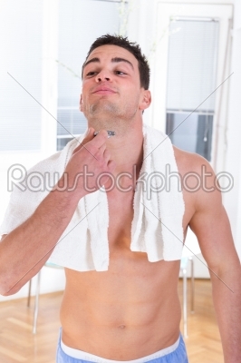 handsome man shaving beard with razor in hand