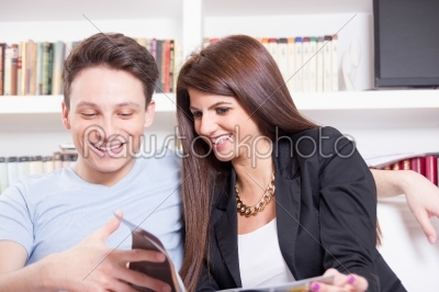 happy couple at home reading magazine
