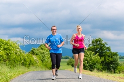 happy couple doing sport jogging on rural street