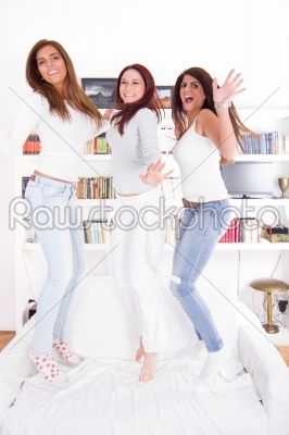 happy party girls jumping on couch