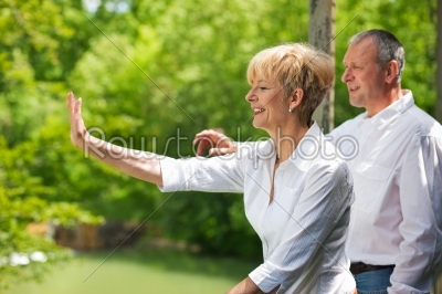 Happy senior couple on bridge waving hands