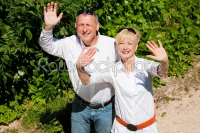 Happy senior couple outdoors waving hands