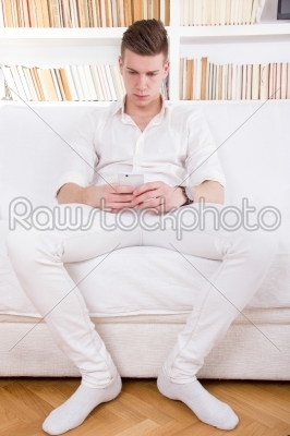 lonely young man in white texting message on cellphone