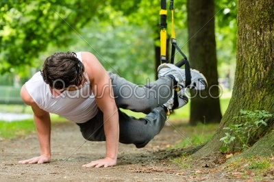 man in city park doing suspension trainer sport