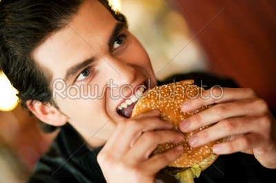 Man in restaurant eating hamburger