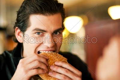 Man in restaurant eating hamburger