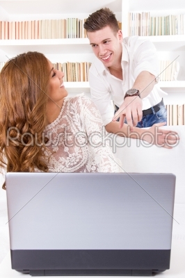 man showing something to his pretty wife on a screen in their li