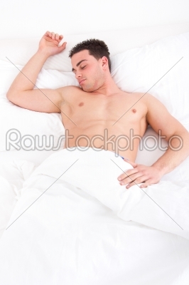 man sleeping in his bed at home with one hand on pillow