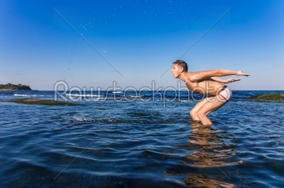 Naked young man coming out from the water