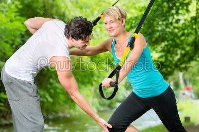 People in park on suspension or sling trainer