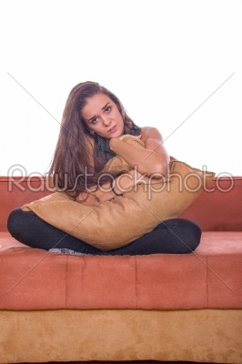 sad girl sitting on the couch and hugging pillow